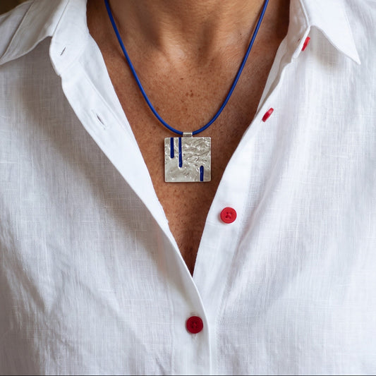 Blue Enamel Square Necklace on a blue cord, worn over a white linen shirt