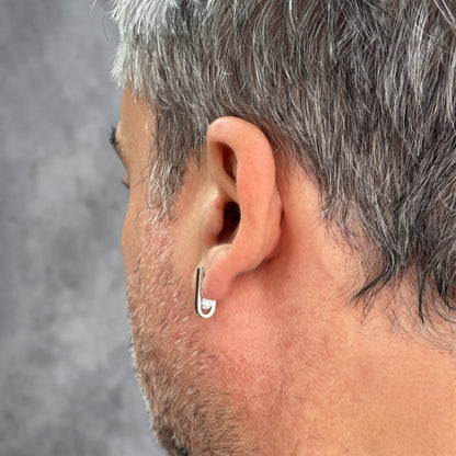 Back view of the J-02 earring on a male model's ear: the curve and clear zircon behind the earlobe
