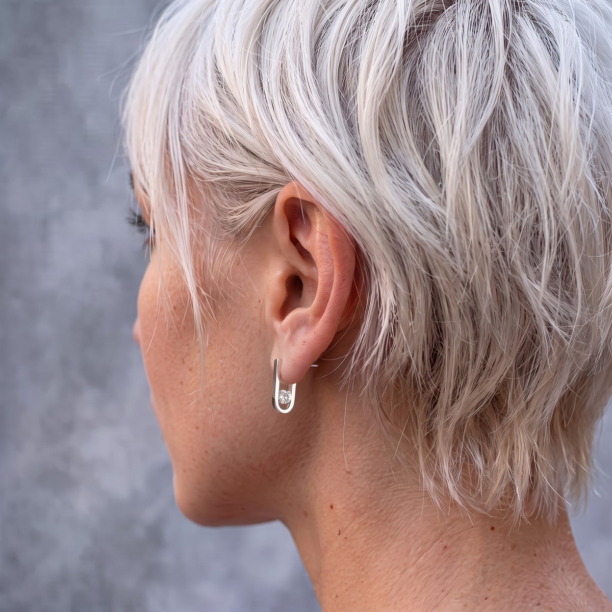 Back view of the J-02 earring on a female model's ear: the curve and clear zircon behind the earlobe