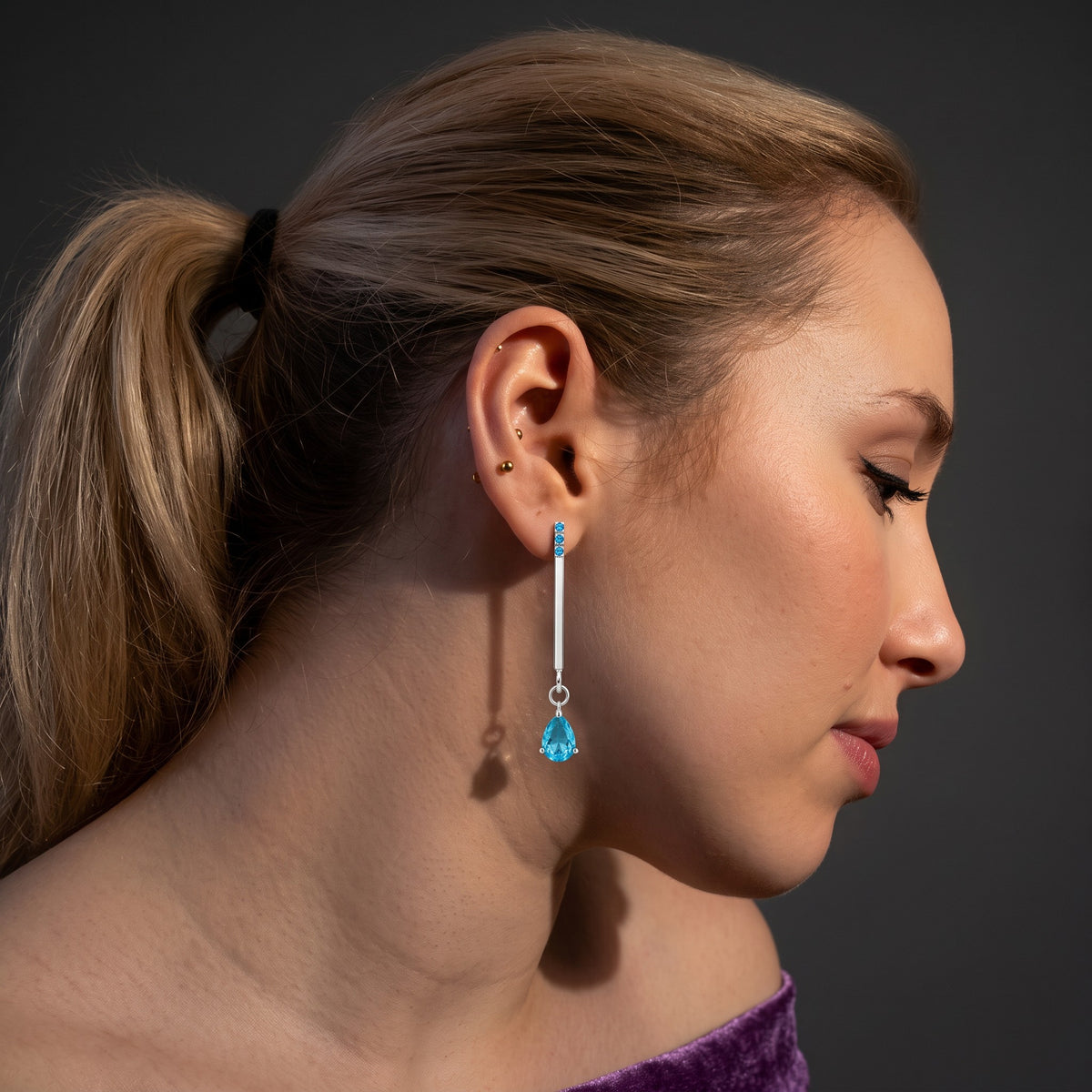 Blue drop earring worn, side view – slim 925 silver line with a moving blue zircon teardrop