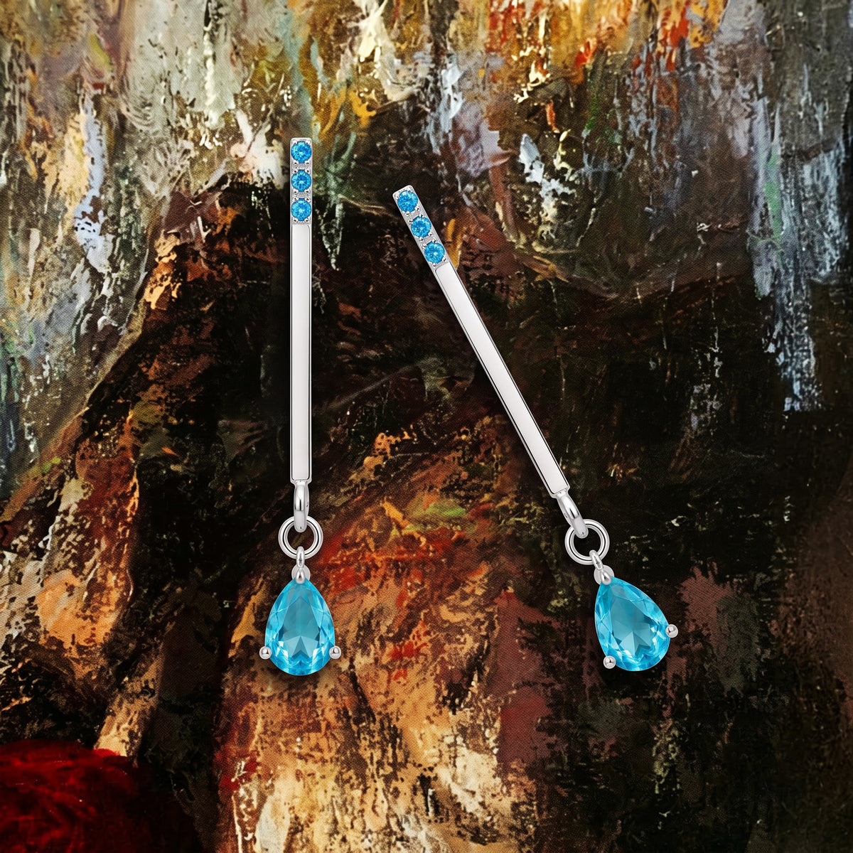 Blue zircon drop earrings on an oil-painting texture