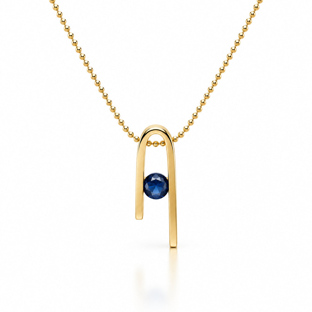 14K gold plated Minimalist n Necklace on a white background: a deep blue zircon at the centre of the n-shaped pendant, with a bead chain running through the form
