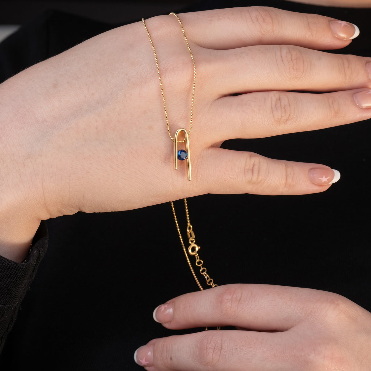 Minimalist n Necklace laid across a hand: the pendant, the bead chain and the clasp