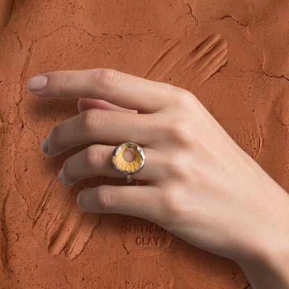 Volcano Ring worn on hand – resting on a textured terracotta clay surface