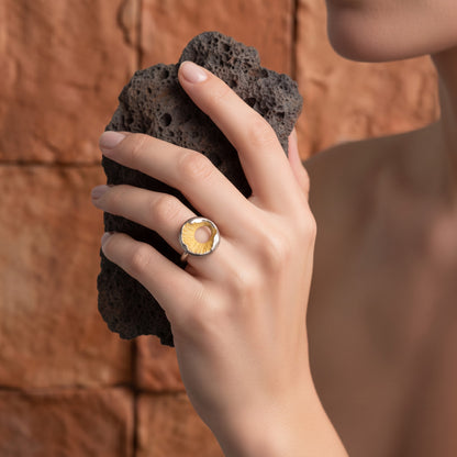 Volcano Ring worn on hand – holding a dark volcanic rock against a terracotta wall